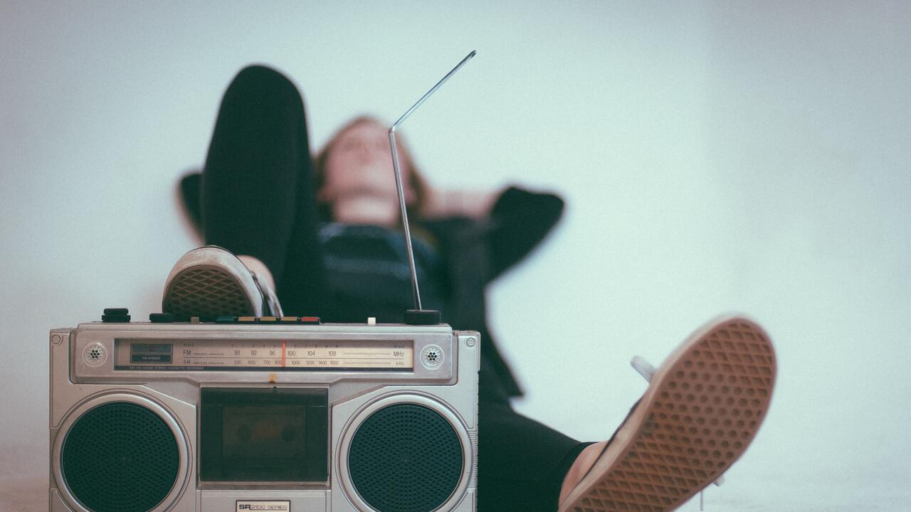 Male person listening to music with his feet against a boombox