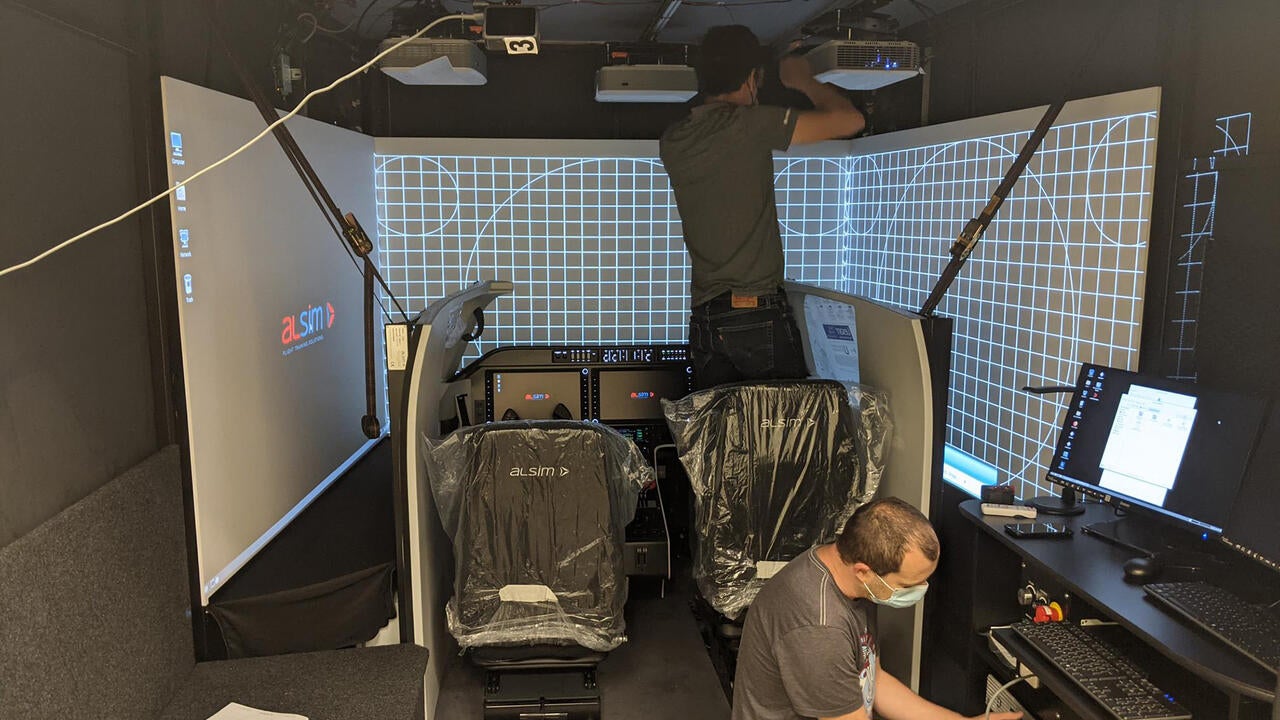 Two people wearing masks installing the flight simulator