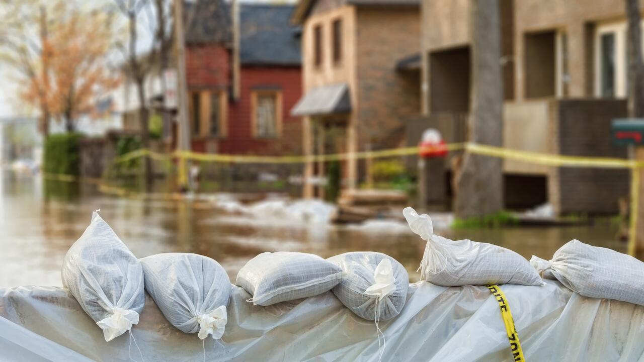 Flooded residential street with sandbags in foreground.