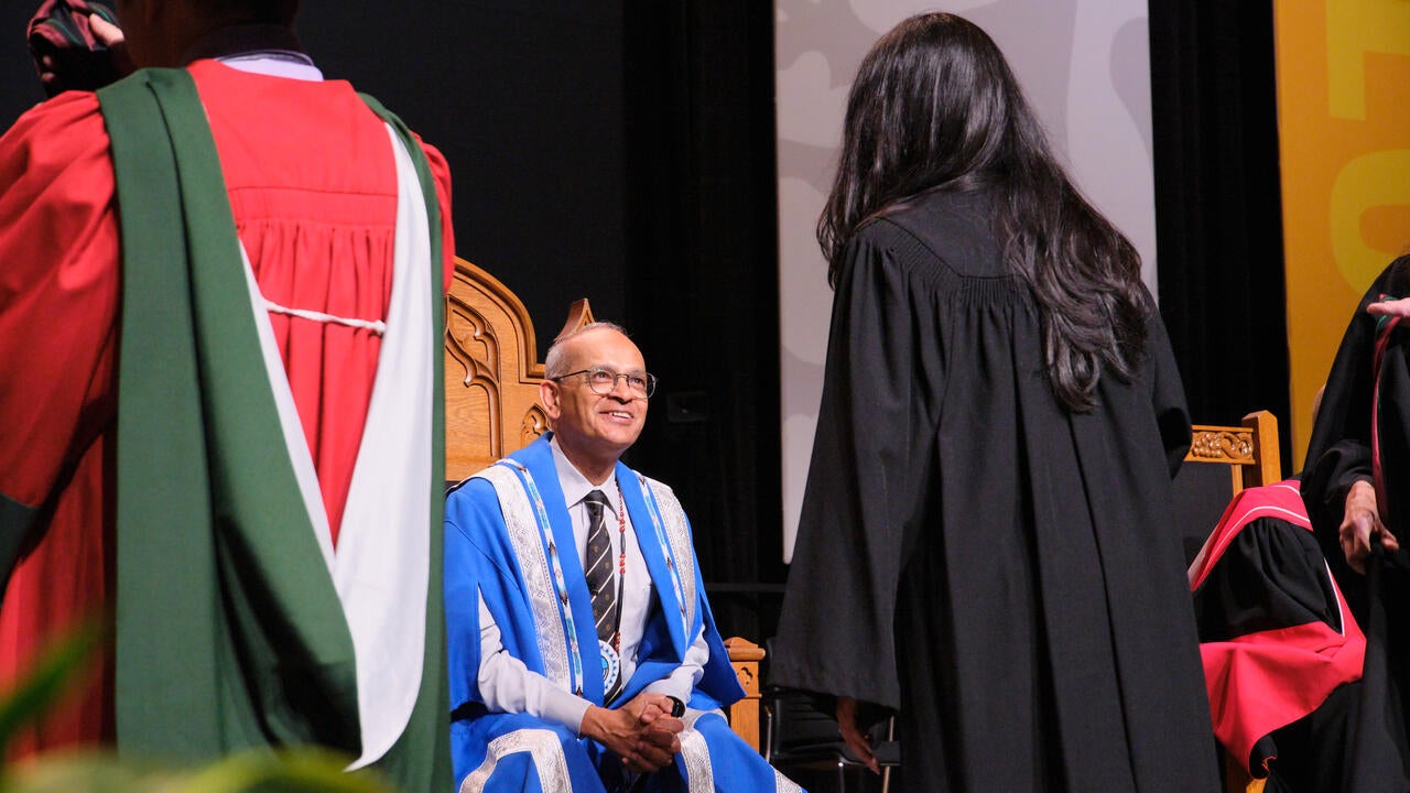 President Goel smiles as he speaks to a graduate during convocation ceremony.