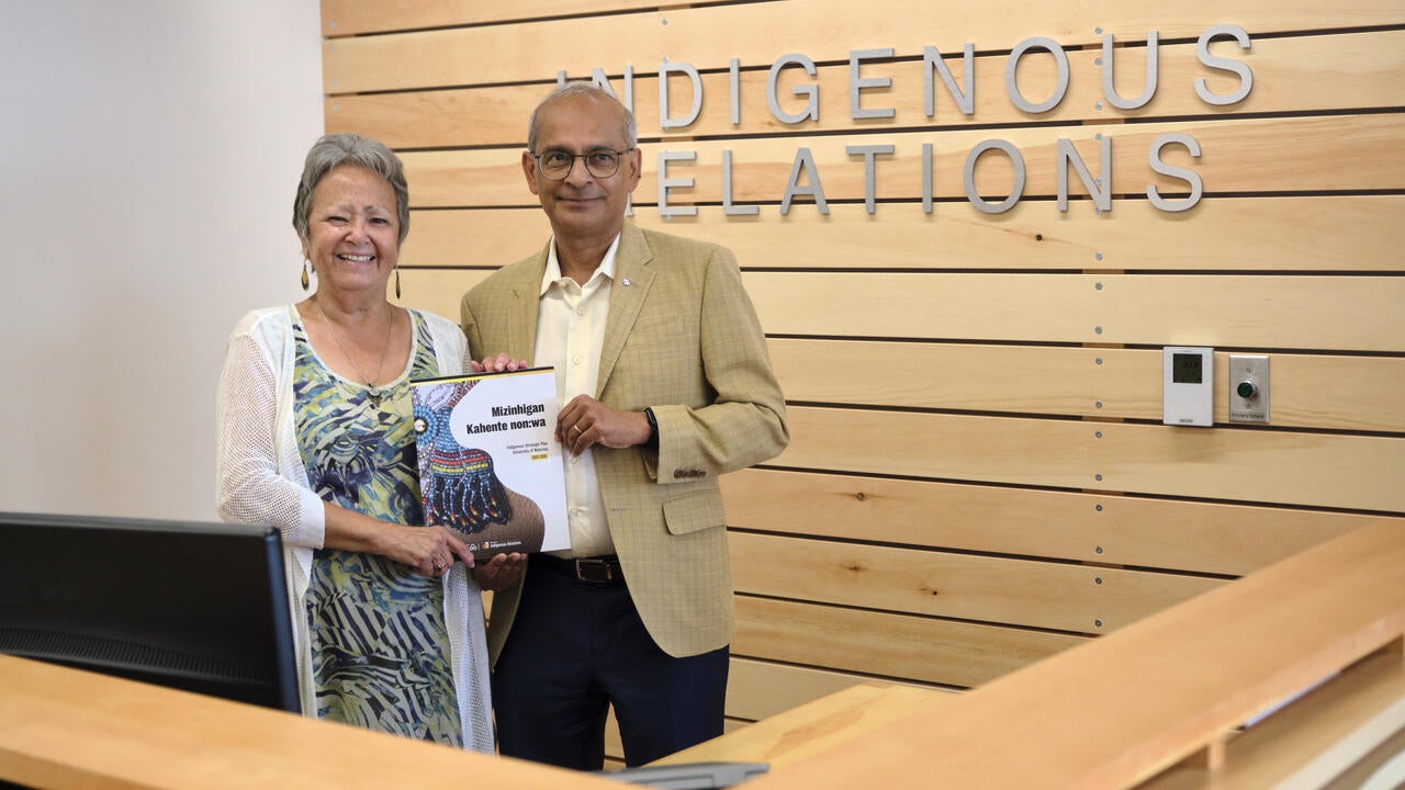Jean Becker and Vivek Goel holding the Indigenous Strategic Plan