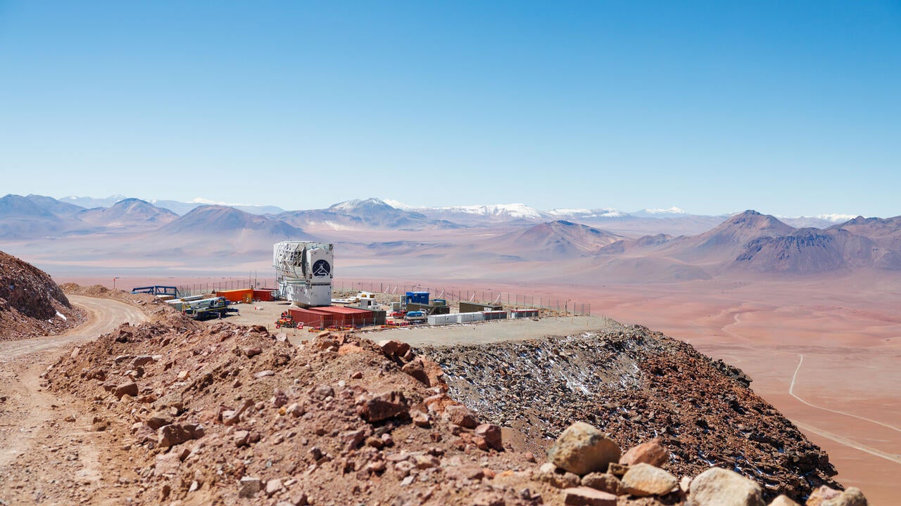 observatory on a cliff edge overlooking an open desert with mountains