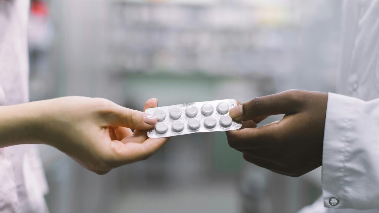 A pharmacist handing pills to a customer