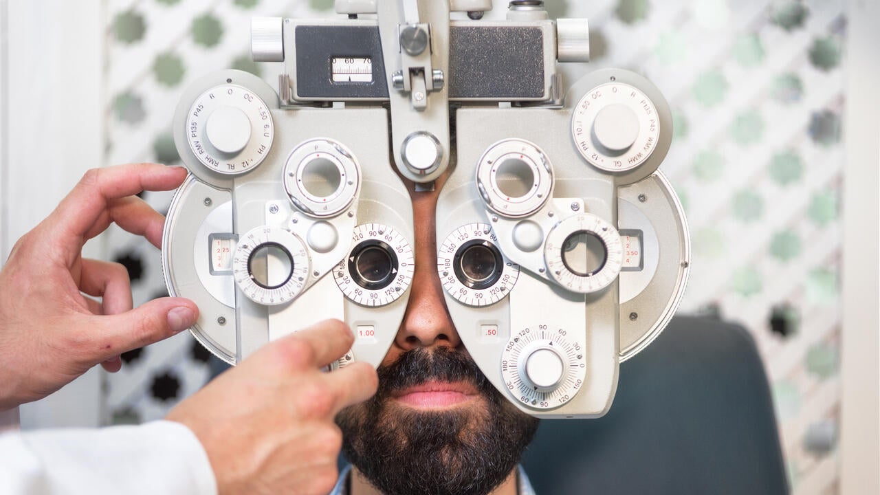 Optometrist doing sight testing for male patient in clinic