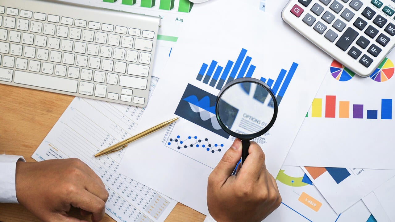 Holding magnifying glass for looking and analysis financial data