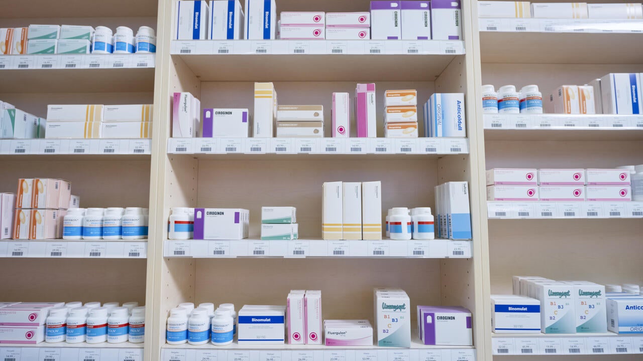 Shelves stacked with medicine bottles and boxes in pharmacy.