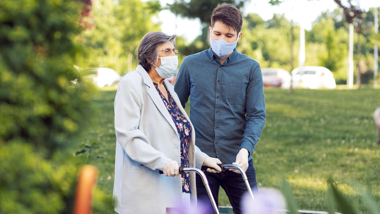 Young man helping senior woman walking in the street 