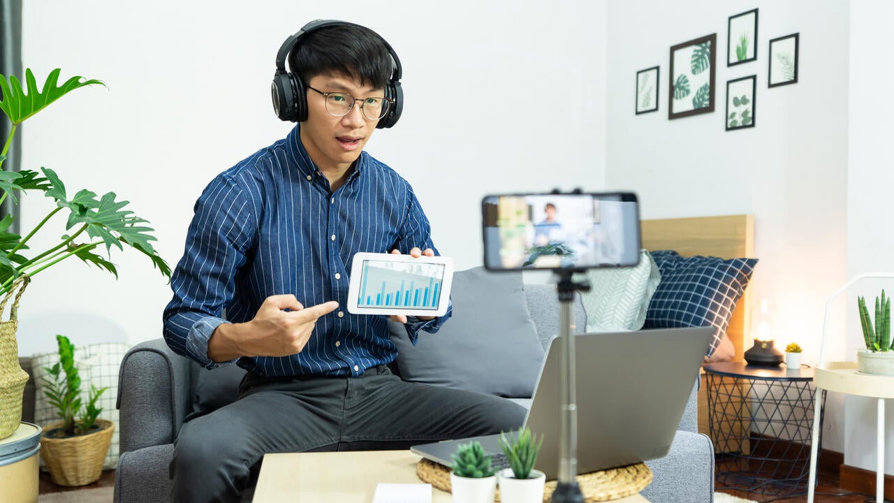 Asian man in headphones writing notes in notebook