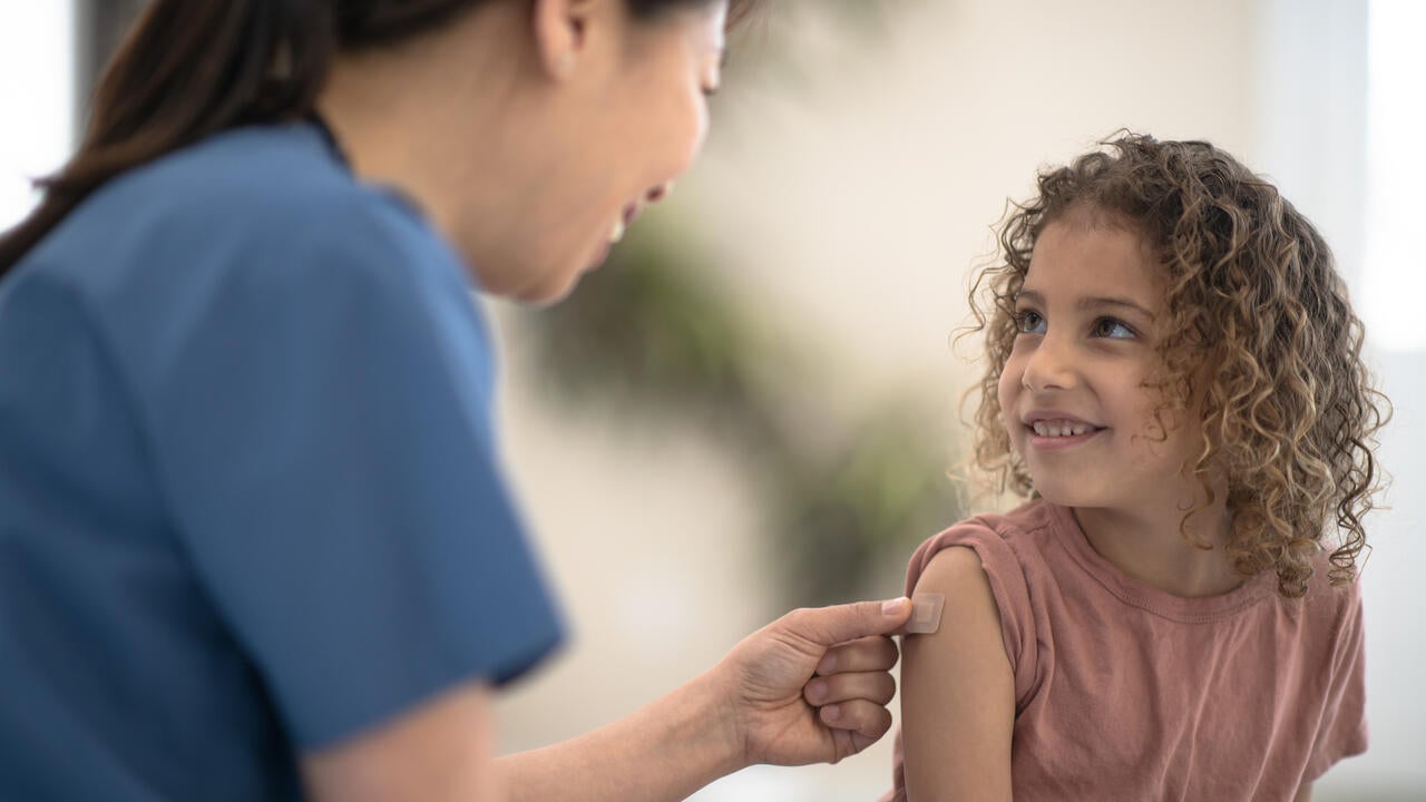 A child gets a bandaid put over their injection site in the doctor's office.