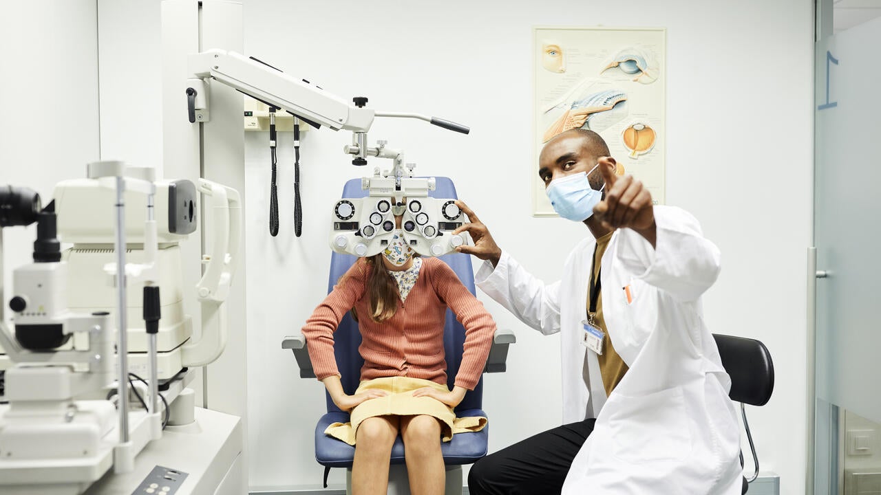 Ophthalmologist gesturing to girl in hospital