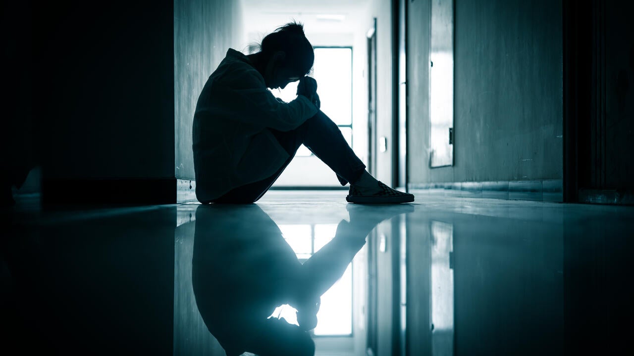 A shadowed teenage girl sitting in a hallway 