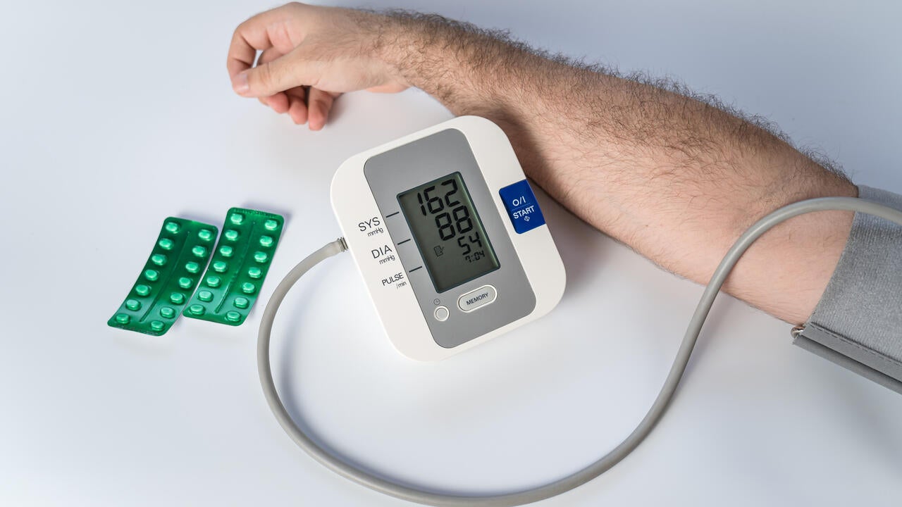 Man's arm with device for taking blood pressure and pills