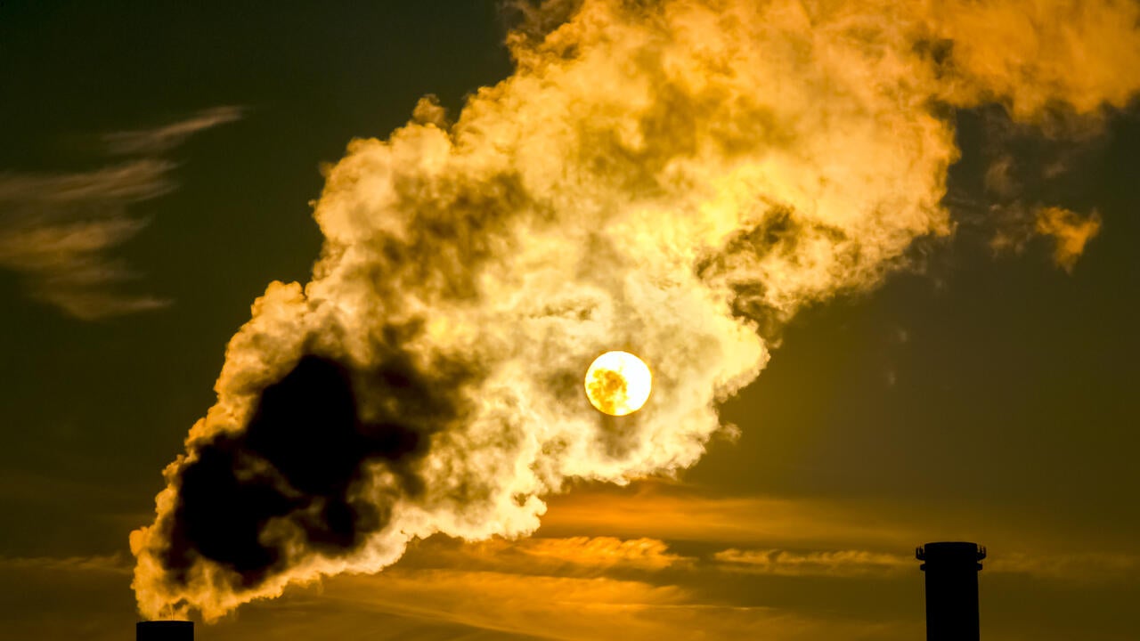 An image of smokestacks emitting smoke during a sunset