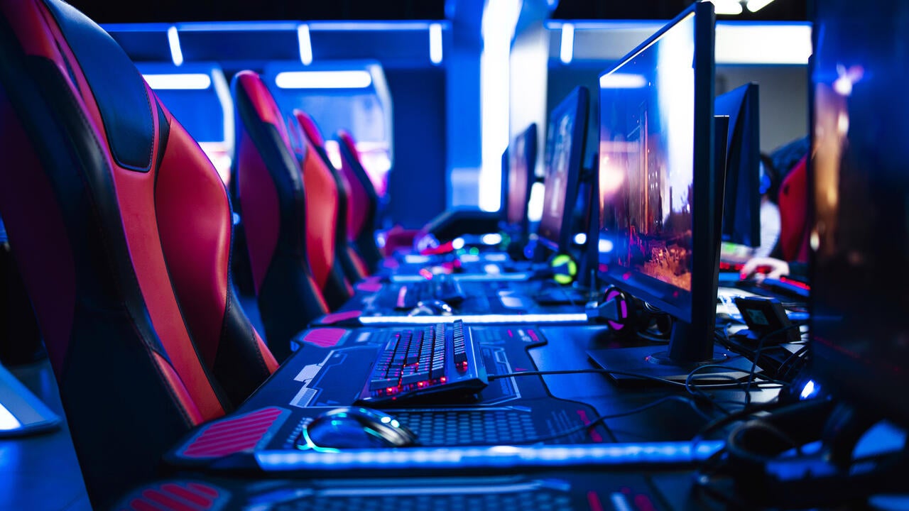 Game room interior with modern ambient lights and powerful super computers, consoles, keyboards for playing video games