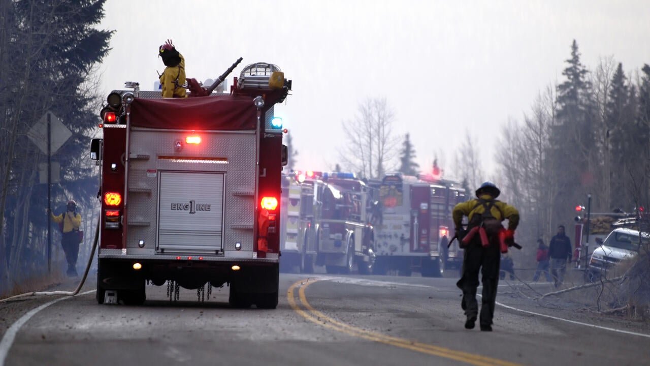 Several firetrucks respond to an active fire scene. 