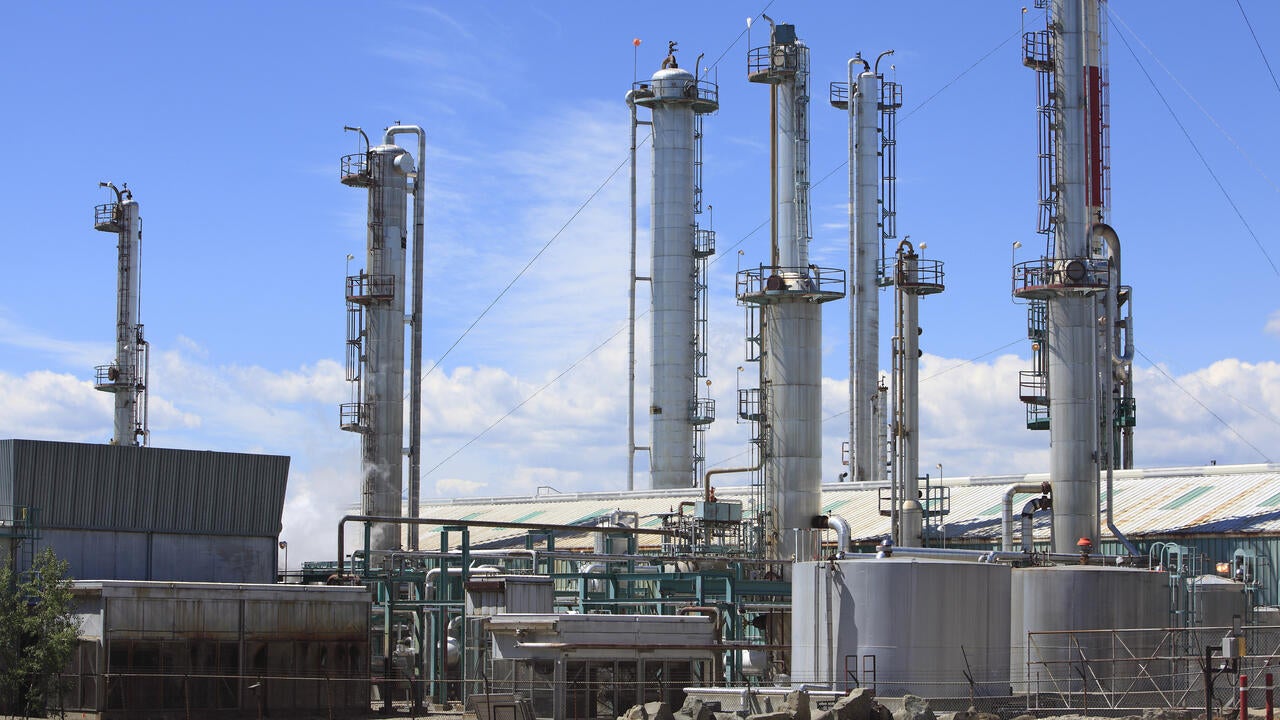 Close up of large gas plant with towers, network of pipes and storage tanks.