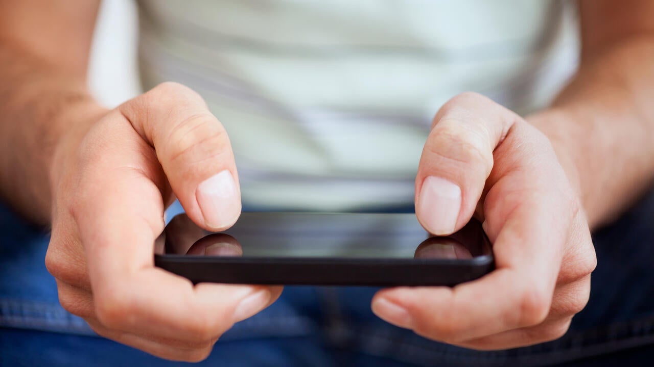 Hands of a casual man using a smartphone.