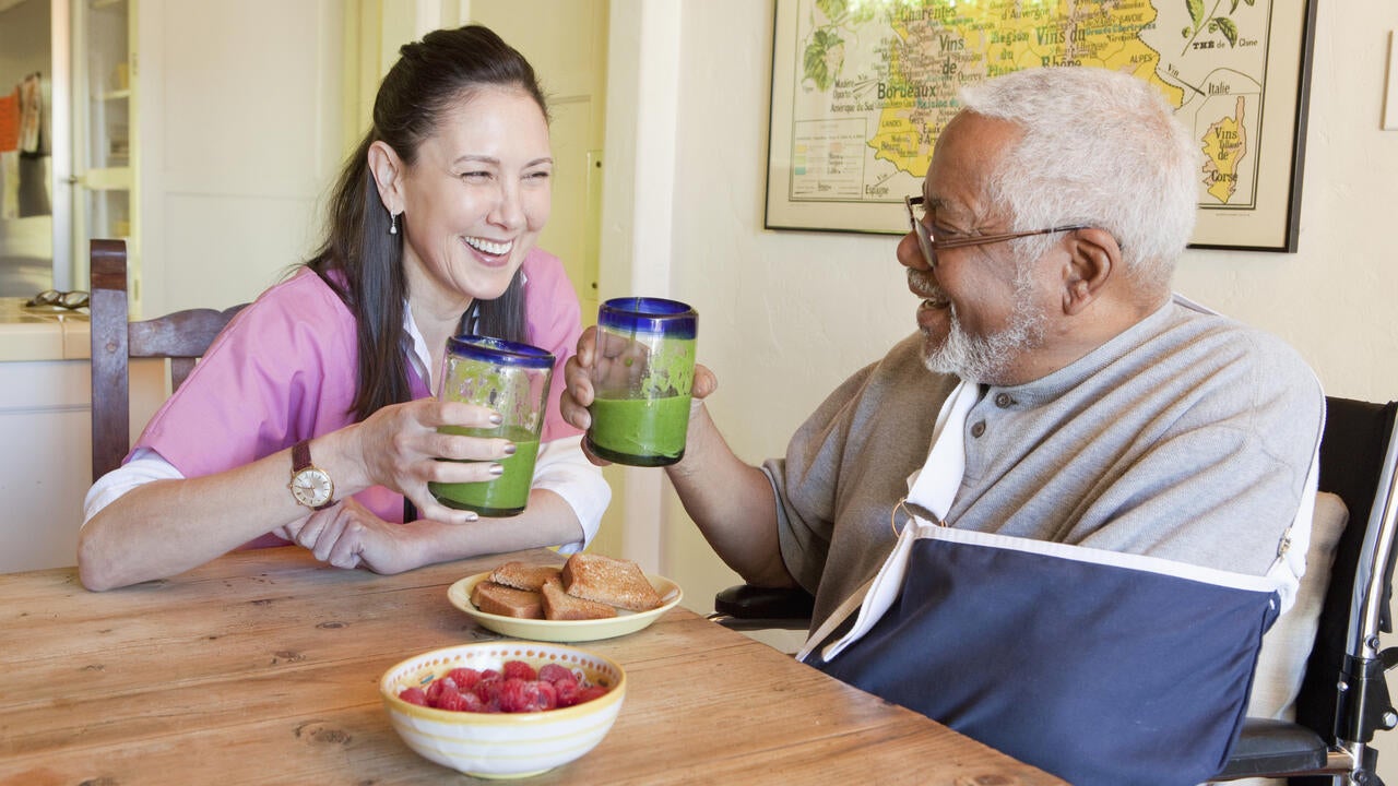 Caretaker and older man having smoothies 