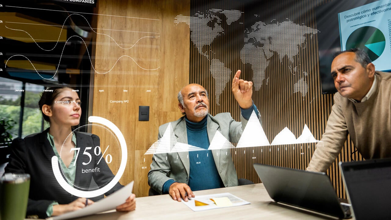 Team of executive leaders pointing at a hologram of the world map 