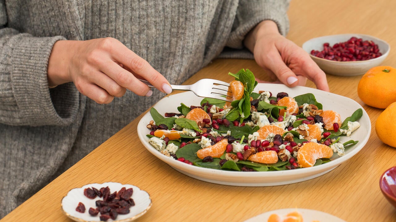 A person eating a winter salad with fresh spinach, mandarin and pomegranate (Getty Images/Victoria Popova).