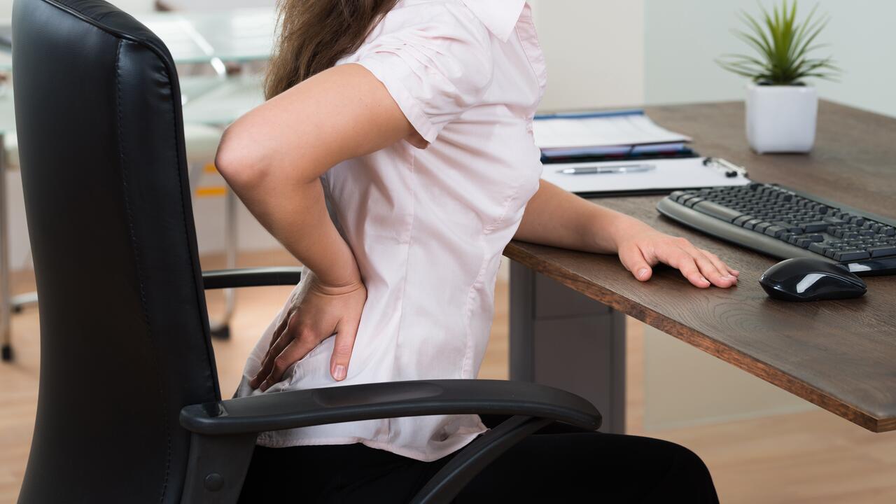 women's back in pain while sitting on chair