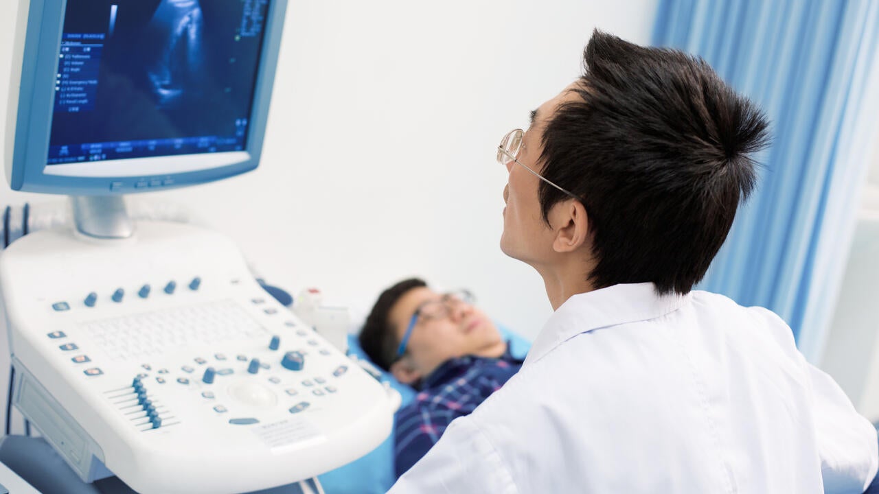 Medical practitioner using ultrasound medical device to examine patient.