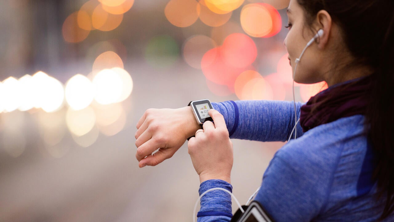 Runner in blue sweater looking at smartwatch