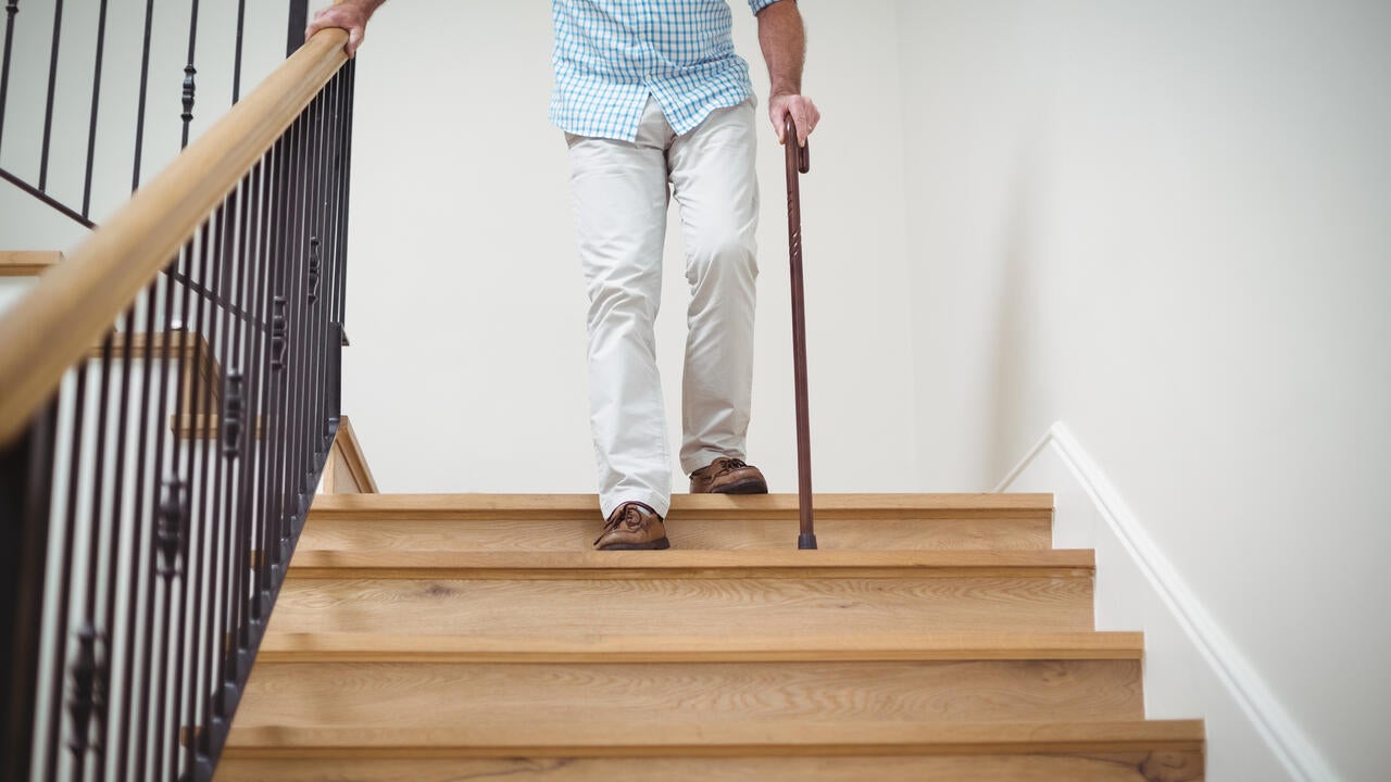 Senior man climbing downstairs with walking stick 