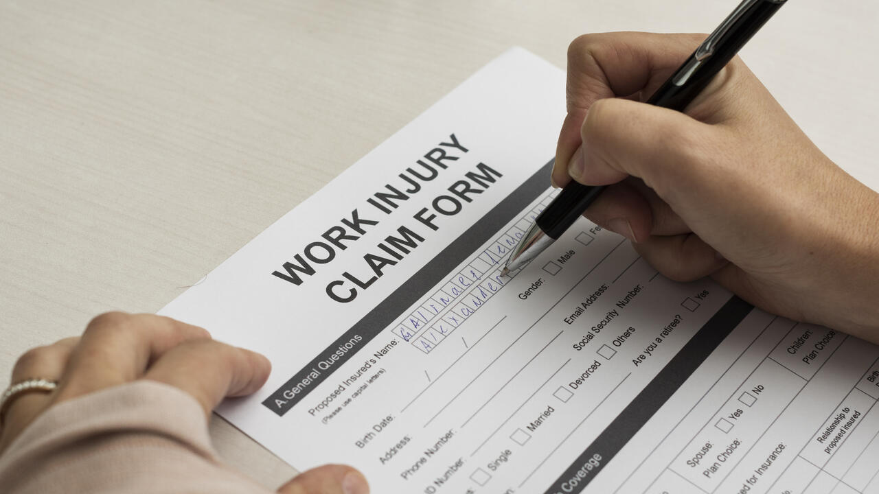 Image of someone signing a work injury claim form