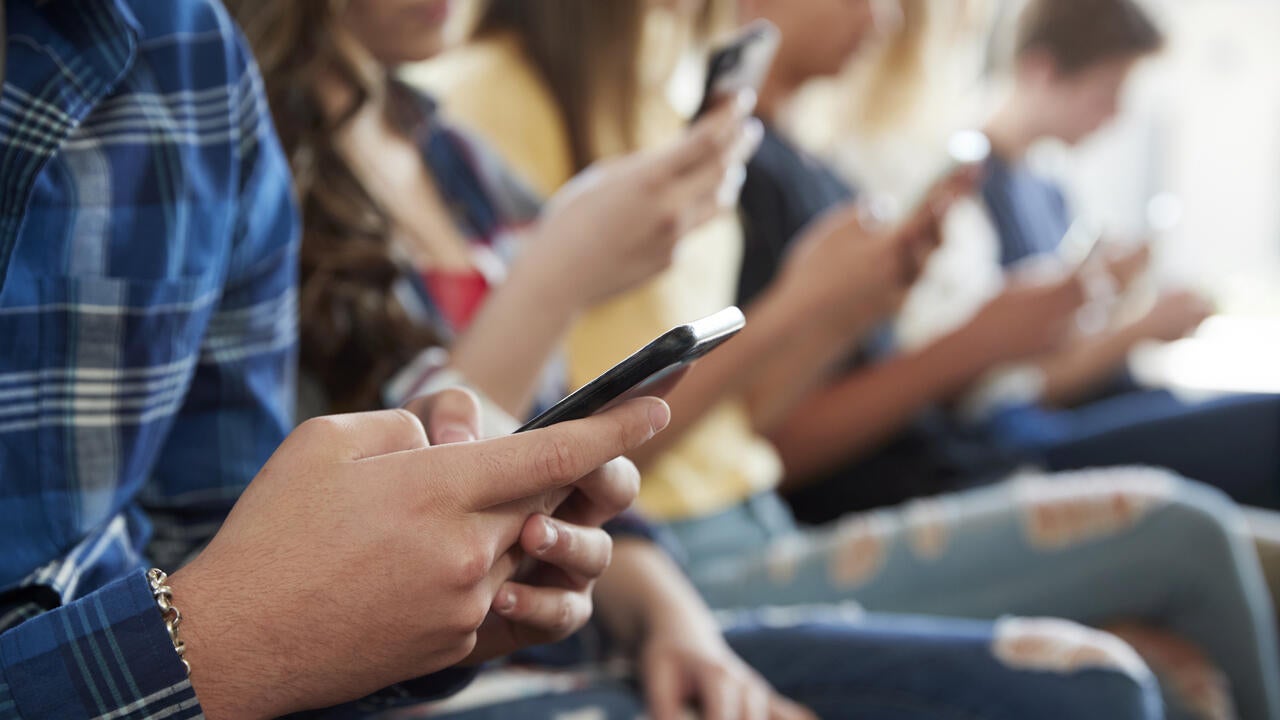 Close up of adolescents using mobile phones 