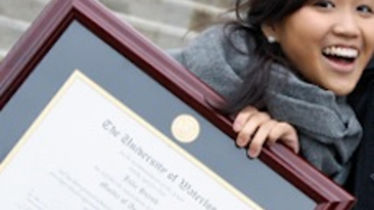 A young woman holds her framed Waterloo degree.