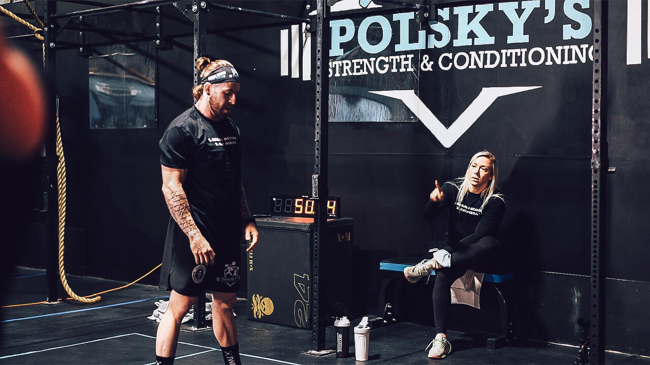 Nick Anapolsky looks at a gym floor while a blond woman looks on