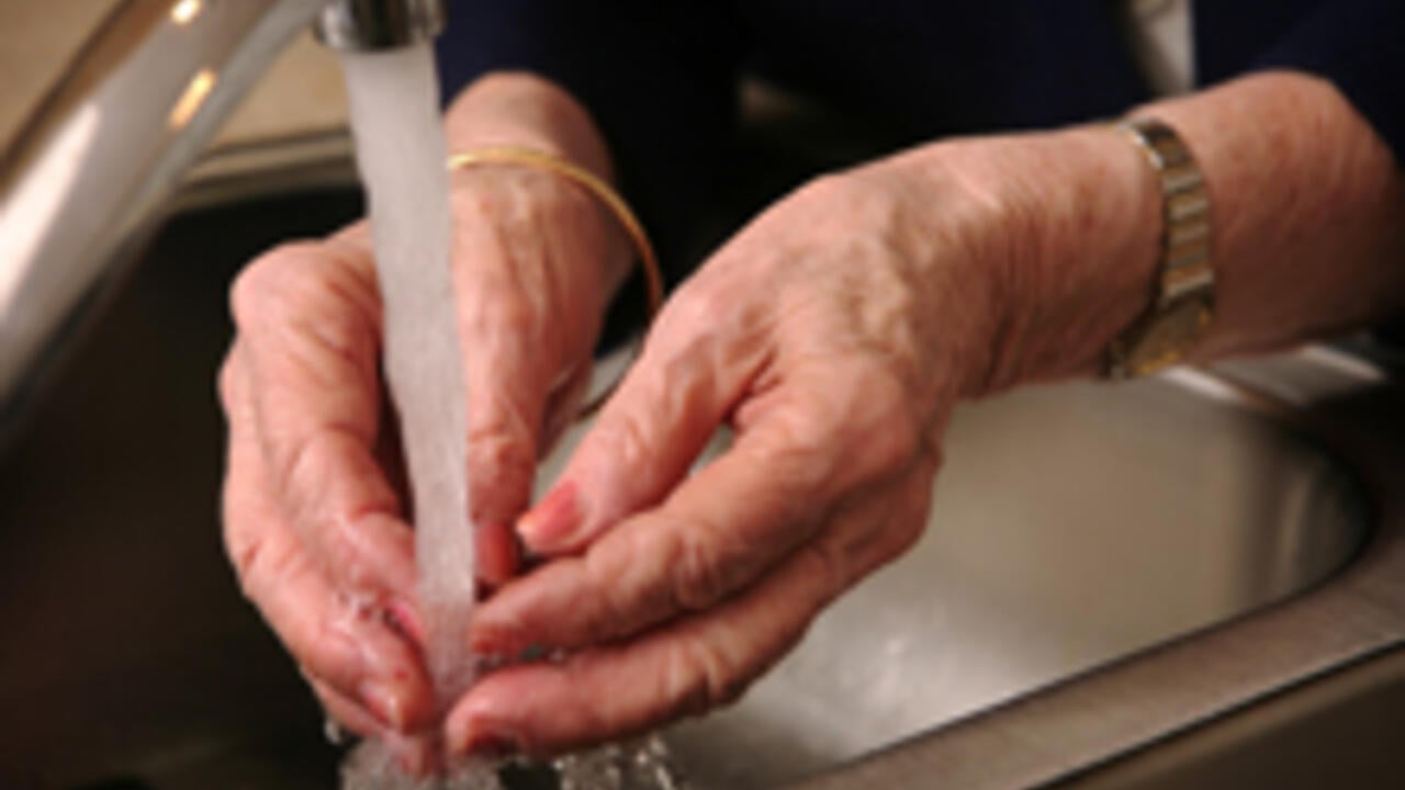 Senior woman's hands under tap