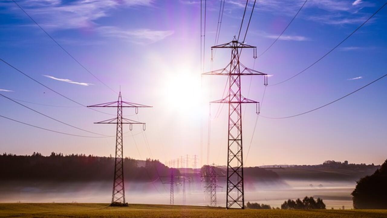 Image of electric towers with sun in the blue sky