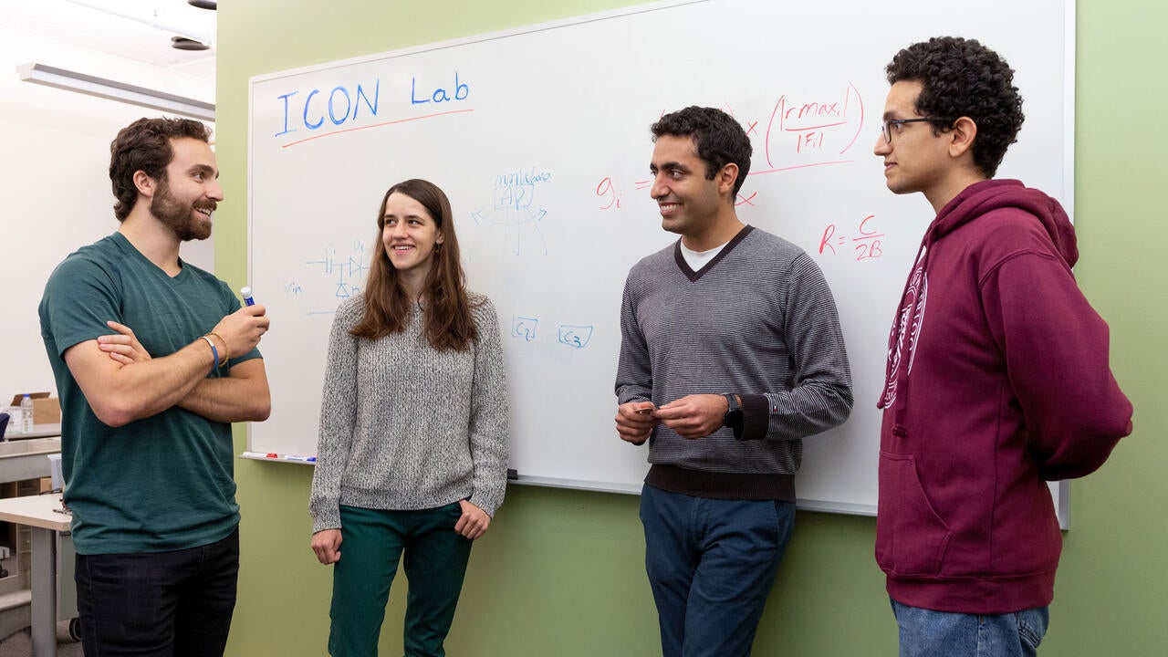 Professor Omid Abari and his students stand beside a white board