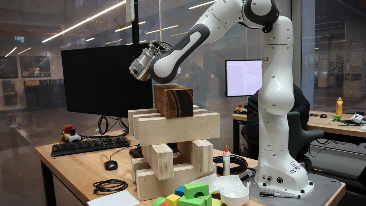 A photo of a robotic arm positioned over building blocks