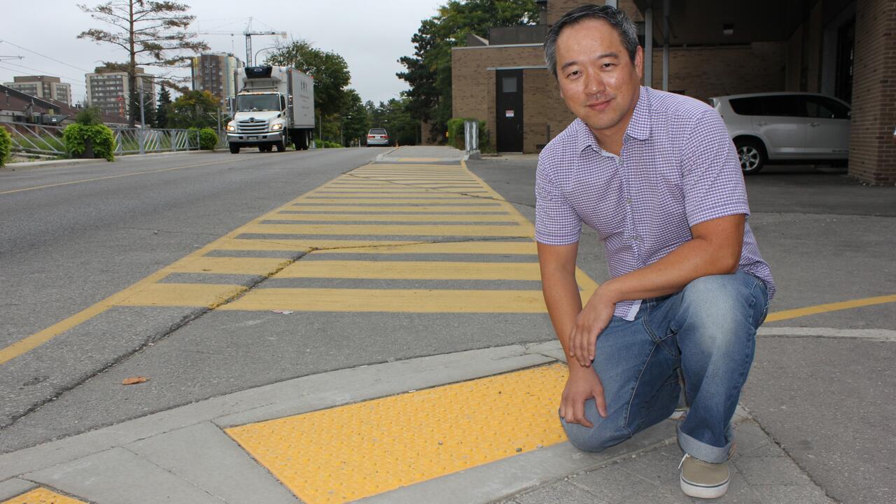 Jim Wei kneeling on a paved road