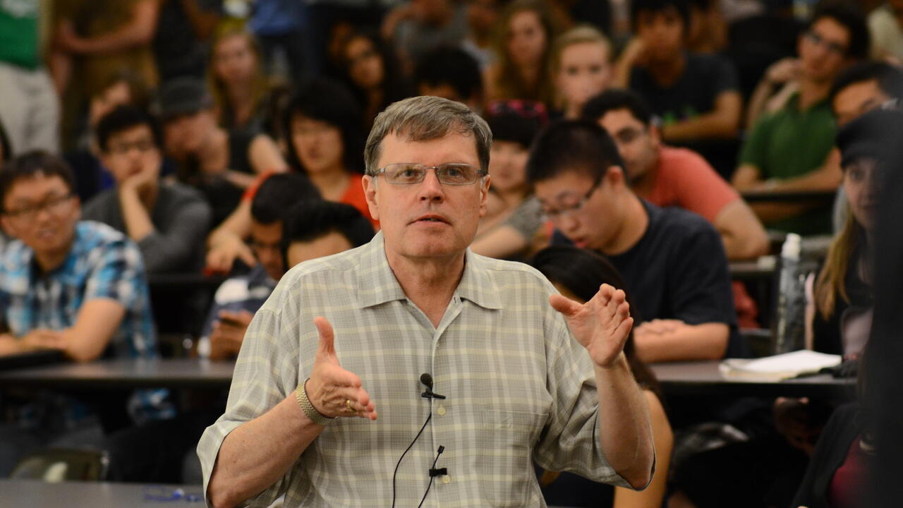 Larry Smith speaking in a background of students 