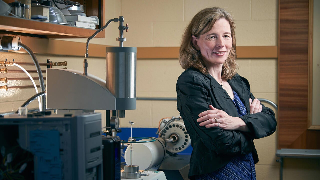 Mary Wells standing with arms crossed, next to lab equipment