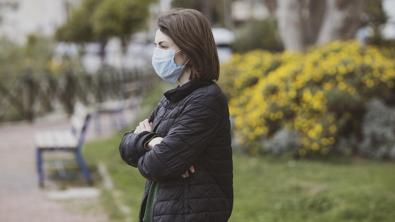 Woman with folded arms wearing a COVID-19 mask.