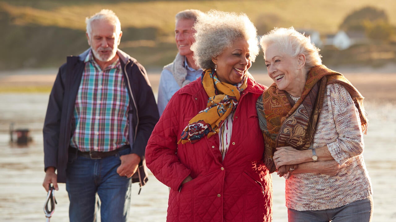 Four older adults walking on a beach