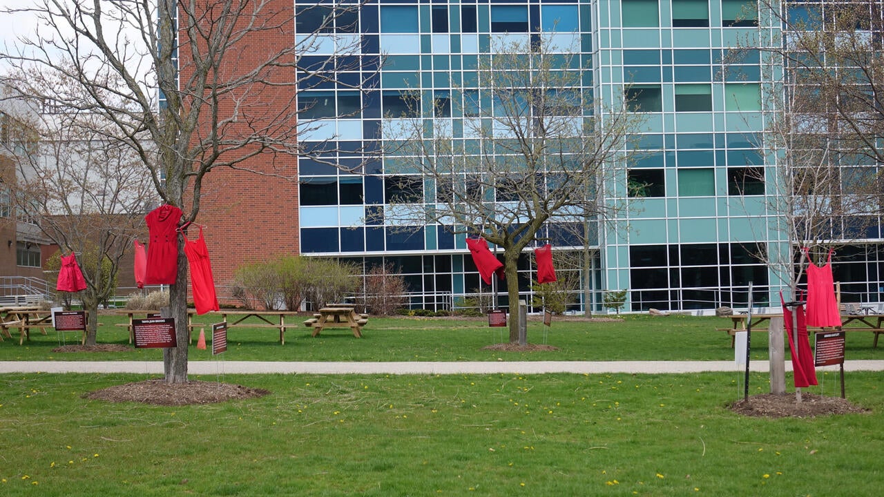 Red dresses hanging from trees in front of the Mathematics building