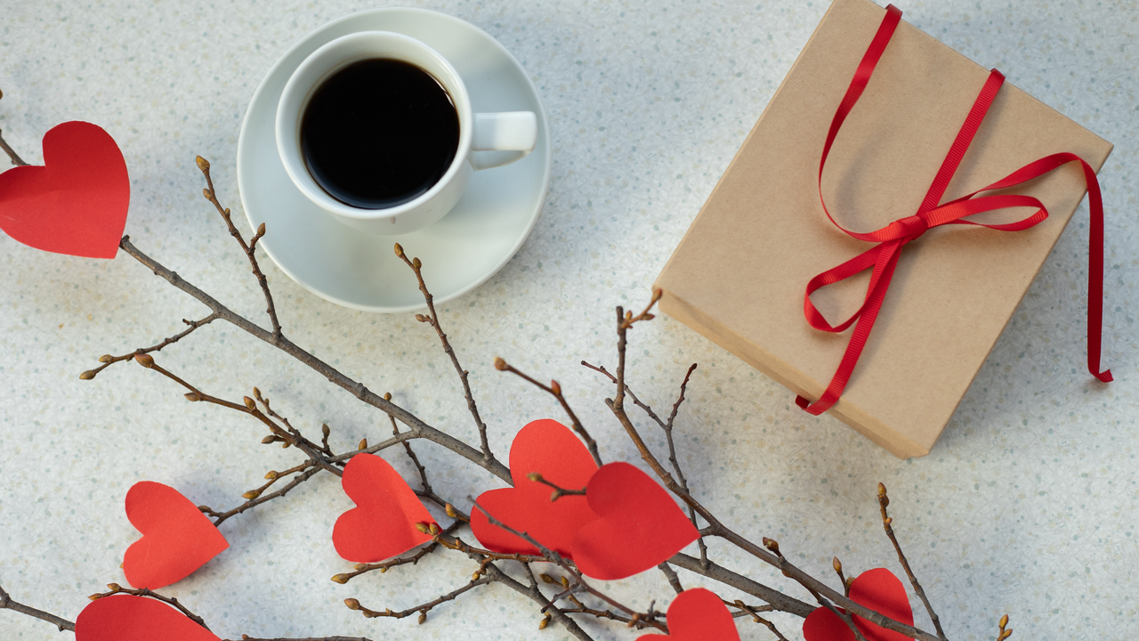 Top-down view of coffee, a gift with a red bow and paper hearts