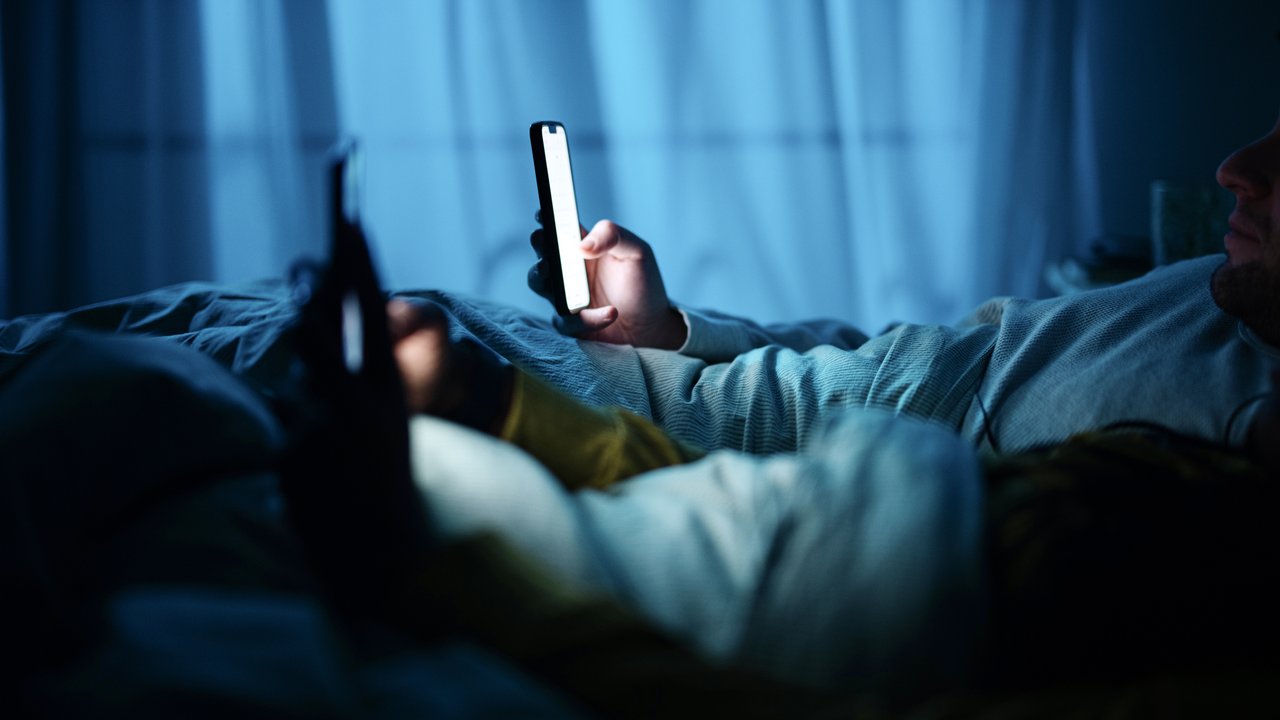 couple using their phones in a dark bedroom