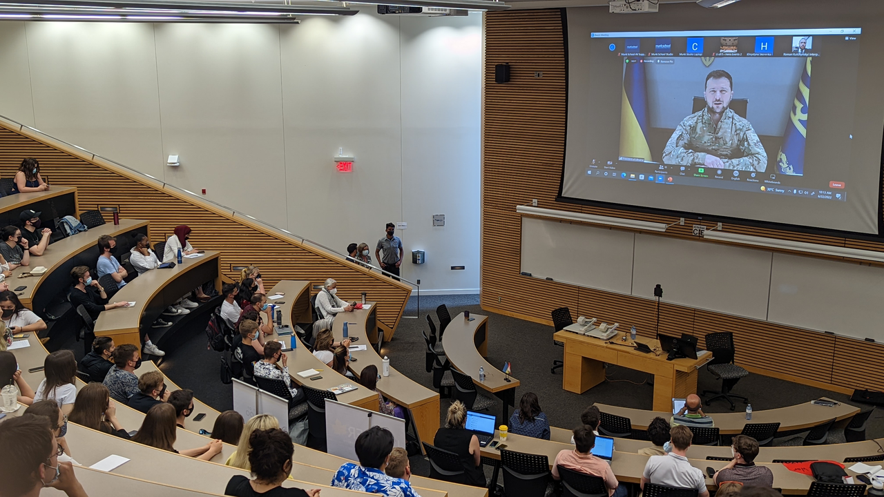 Lecture hall filled with students watching live-stream event