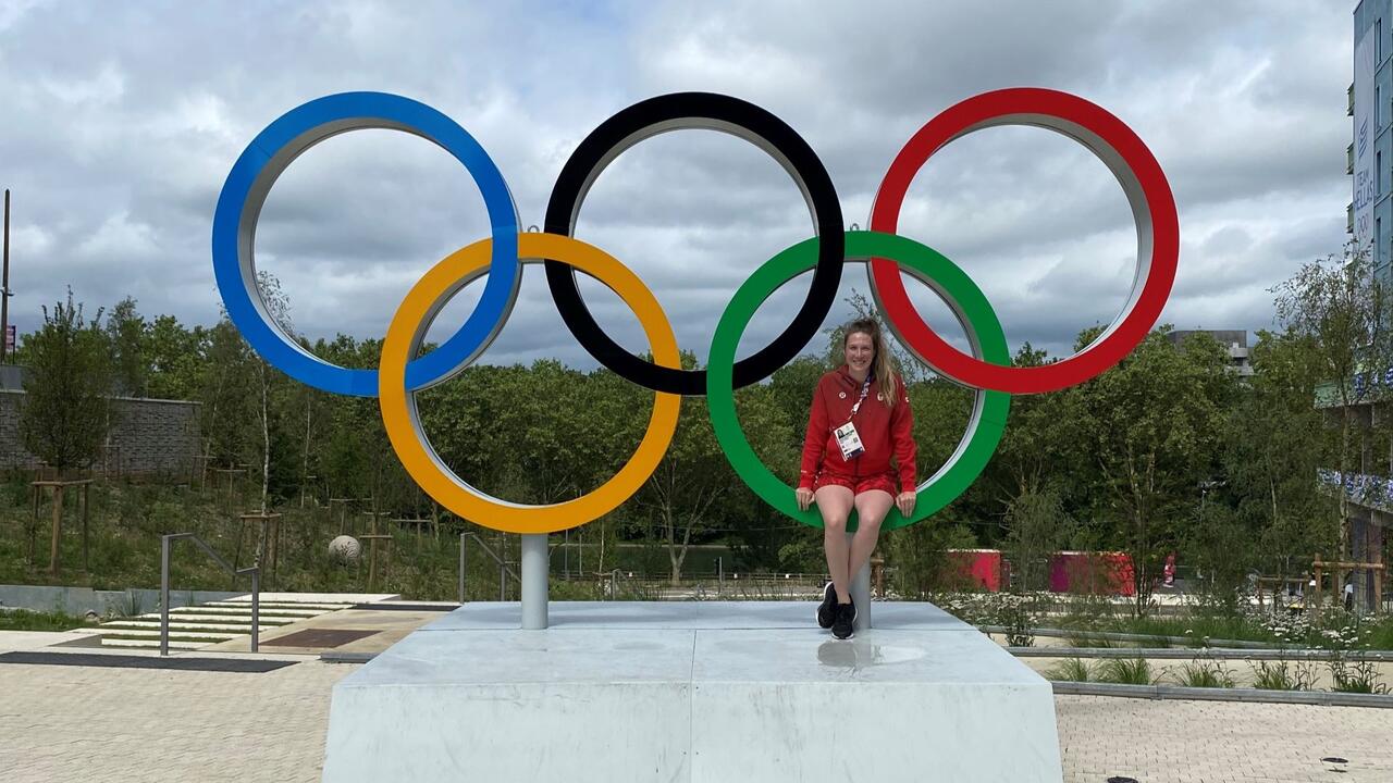 Amarah Epp-Stobbe sits in one of the five Olympic rings of a large statue.