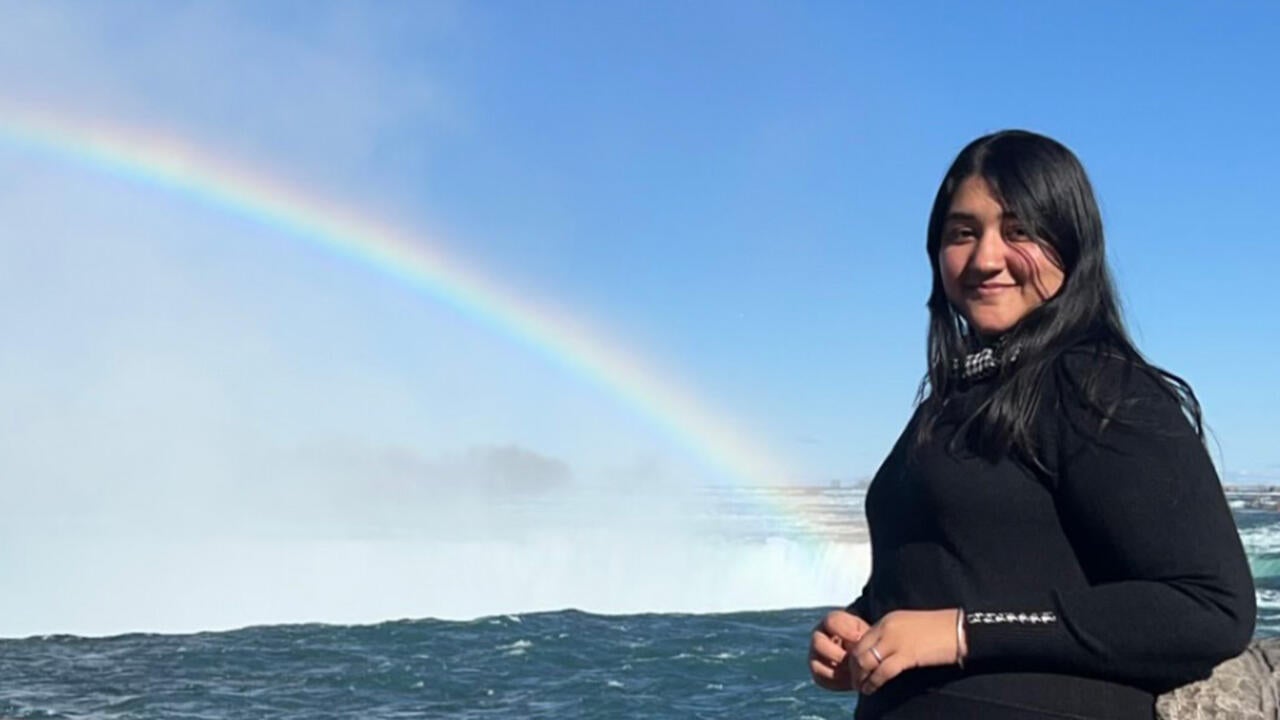 Pallavi standing by waterfalls with a rainbow behind