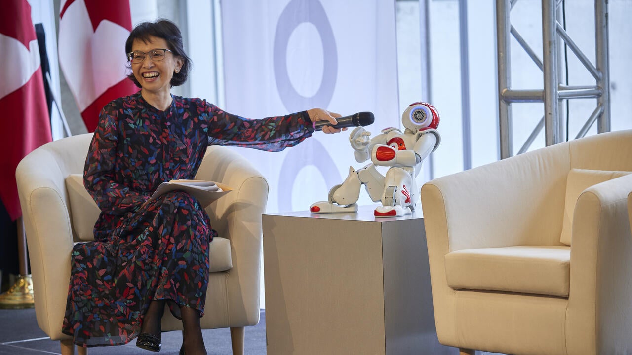 Pearl Sullivan holding a microphone in front of a NAO robot
