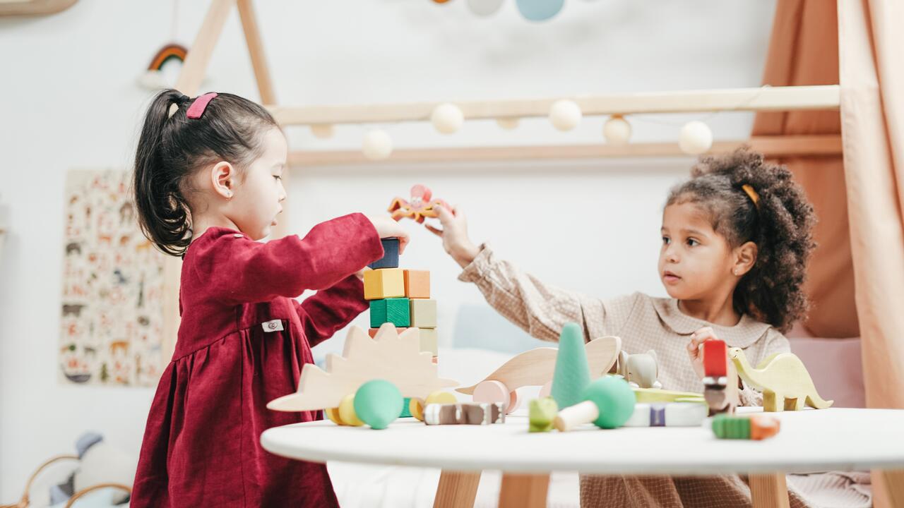 Two girls play with toys in a daycare centre