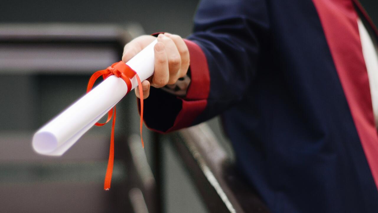 Hand holding out a graduation diploma